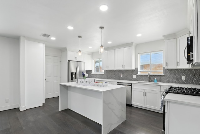 9226 Kapri Ln, Houston, TX 77025 - kitchen featuring appliances with stainless steel finishes, a center island, backsplash, white cabinetry, and healthy amount of natural light