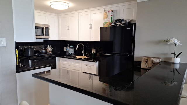7510 Hornwood, Houston, TX 77036 - kitchen with stainless steel microwave, freestanding refrigerator, dark countertops, white cabinetry, and decorative backsplash