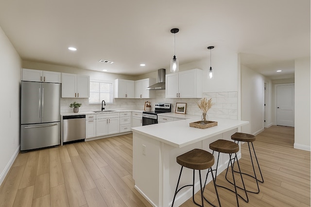 904 Dumas Dr, Bryan, TX 77803 - kitchen featuring appliances with stainless steel finishes, wall chimney range hood, a peninsula, backsplash, and recessed lighting