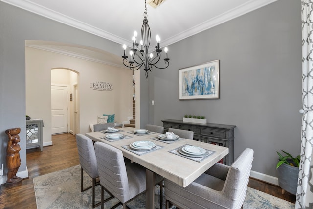 9523 Sapphire Hill Ln, Katy, TX 77494 - dining space featuring arched walkways, crown molding, dark wood-style flooring, a chandelier, and stairs