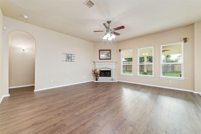 21739 W Mulberry Field Cir, Cypress, TX 77433 - unfurnished living room with arched walkways, a ceiling fan, wood finished floors, and a fireplace with raised hearth