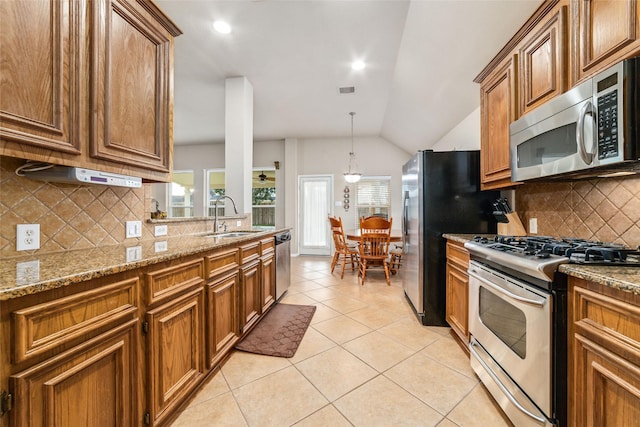 21739 W Mulberry Field Cir, Cypress, TX 77433 - kitchen with stainless steel appliances, brown cabinets, vaulted ceiling, light tile patterned floors, and backsplash