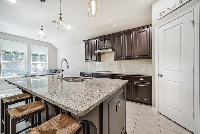 30806 Meadow Wood Dr, Fulshear, TX 77441 - kitchen featuring decorative backsplash, a breakfast bar area, light stone countertops, a center island with sink, and hanging light fixtures