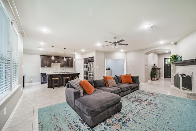 30806 Meadow Wood Dr, Fulshear, TX 77441 - living room with light tile patterned flooring, arched walkways, ceiling fan, recessed lighting, and a brick fireplace
