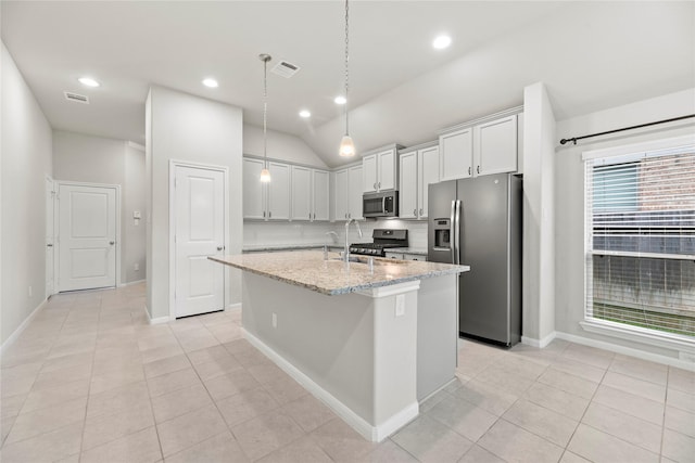 31222 S Pinebrook Falls Ln S, Hockley, TX 77447 - kitchen with appliances with stainless steel finishes, a center island with sink, light stone countertops, light tile patterned floors, and lofted ceiling