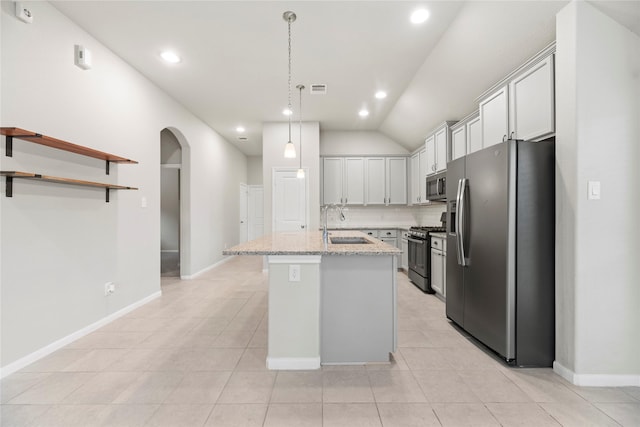 31222 S Pinebrook Falls Ln S, Hockley, TX 77447 - kitchen featuring appliances with stainless steel finishes, arched walkways, an island with sink, hanging light fixtures, and light stone counters