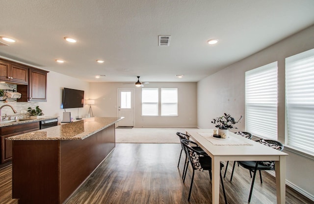 14746 Jasper Stream Ct, Houston, TX 77069 - kitchen featuring wood finished floors, a center island, light stone countertops, a ceiling fan, and backsplash