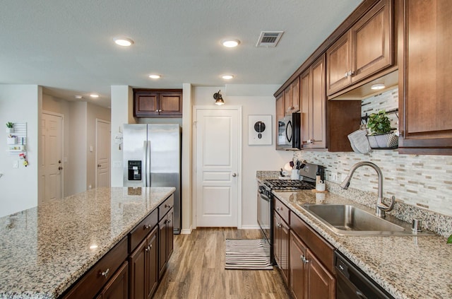 14746 Jasper Stream Ct, Houston, TX 77069 - kitchen featuring appliances with stainless steel finishes, light wood finished floors, backsplash, light stone countertops, and recessed lighting