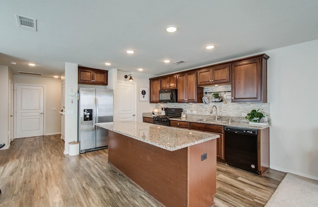 14746 Jasper Stream Ct, Houston, TX 77069 - kitchen featuring black appliances, light wood-style flooring, tasteful backsplash, a kitchen island, and light stone countertops