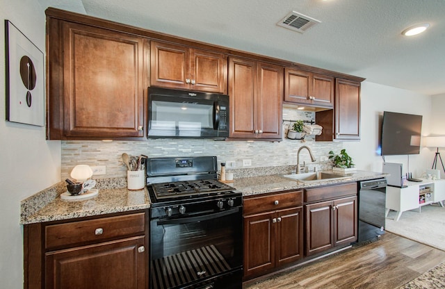 14746 Jasper Stream Ct, Houston, TX 77069 - kitchen with black appliances, dark wood-style flooring, tasteful backsplash, and light stone counters