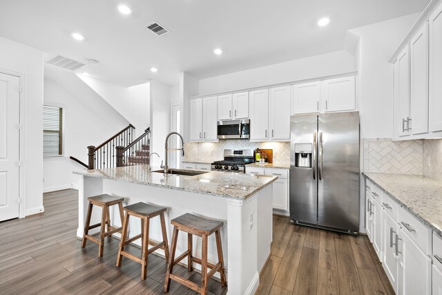 11008 Mikula Dr, Houston, TX 77043 - kitchen featuring appliances with stainless steel finishes, dark wood finished floors, a kitchen island with sink, a kitchen breakfast bar, and recessed lighting