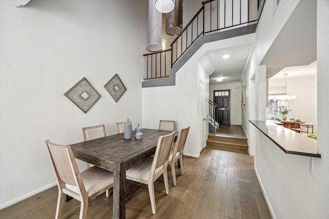 1228 Fountain View Dr Unit 180, Houston, TX 77057 - dining space with stairs, hardwood / wood-style flooring, a towering ceiling, and a chandelier