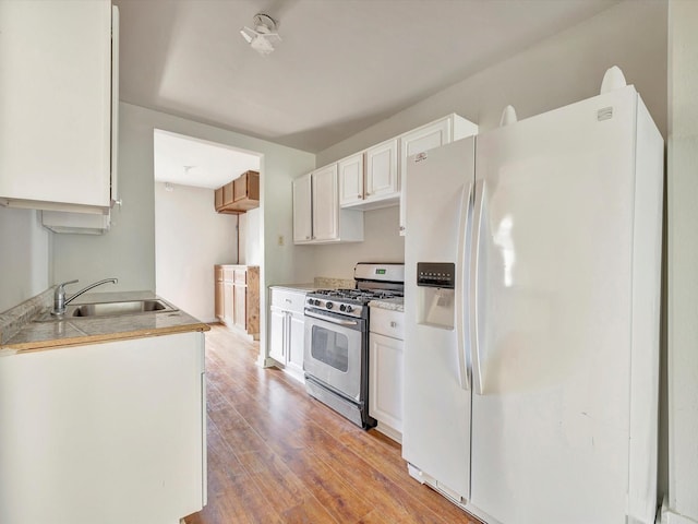 1214 W 6th St, Freeport, TX 77541 - kitchen with white fridge with ice dispenser, stainless steel gas range, light wood-type flooring, white cabinets, and light countertops