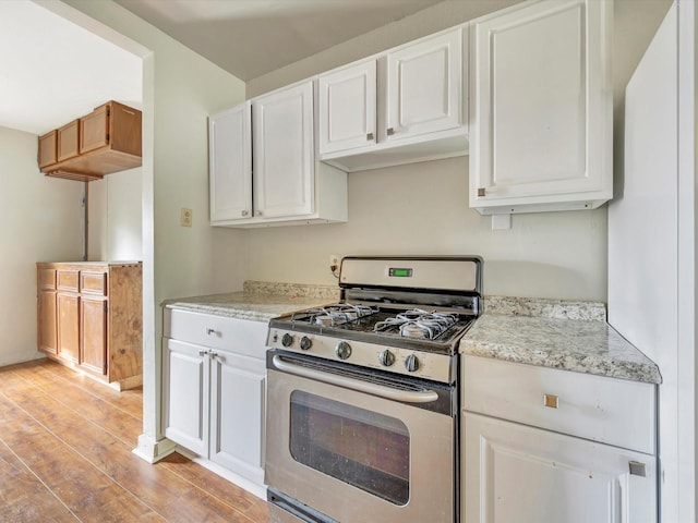 1214 W 6th St, Freeport, TX 77541 - kitchen with gas range, light wood-style floors, white cabinets, and light stone countertops