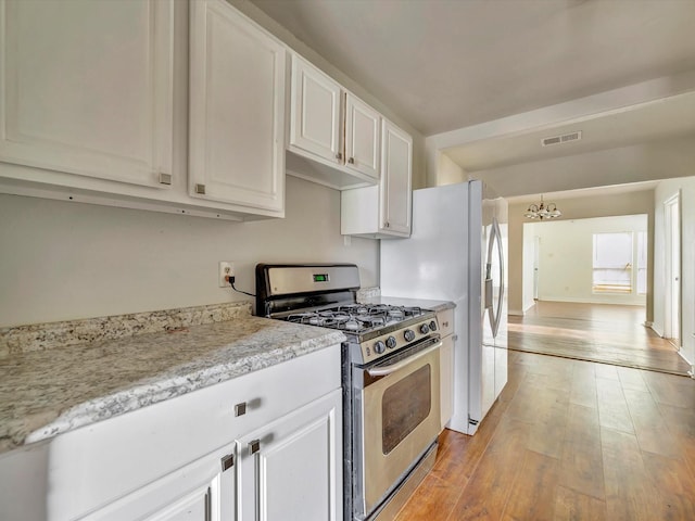 1214 W 6th St, Freeport, TX 77541 - kitchen featuring stainless steel range with gas cooktop, a chandelier, white cabinetry, and light wood-type flooring