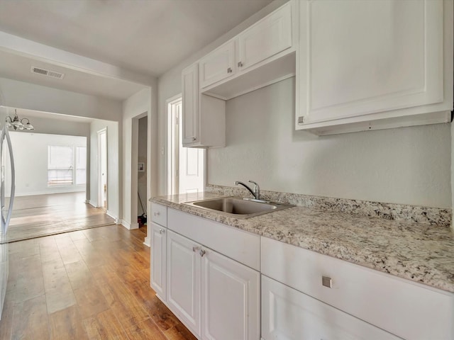 1214 W 6th St, Freeport, TX 77541 - kitchen featuring light wood-type flooring, white cabinets, a chandelier, and light stone counters