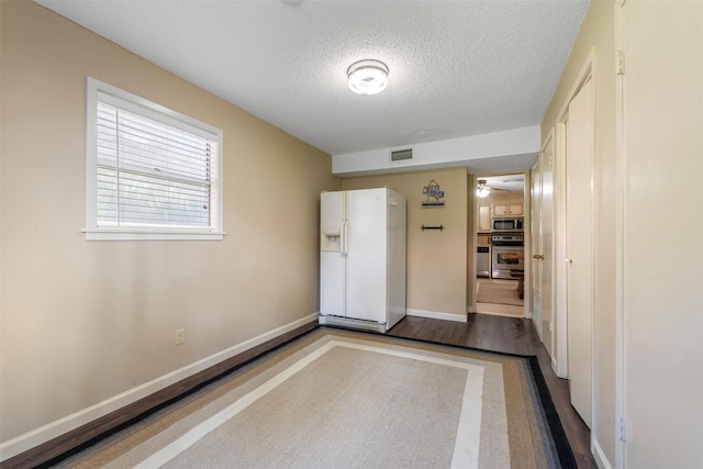 1831 Lakeview Estates Dr, Coldspring, TX 77331 - unfurnished bedroom featuring white fridge with ice dispenser, a textured ceiling, and wood finished floors