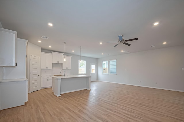 14979 Eagle Feather Dr, Houston, TX 77090 - kitchen with light wood-style flooring, an island with sink, recessed lighting, open floor plan, and white cabinetry