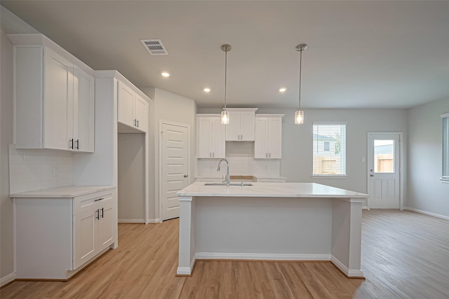 14979 Eagle Feather Dr, Houston, TX 77090 - kitchen with light wood-style floors, decorative backsplash, a center island with sink, white cabinets, and recessed lighting