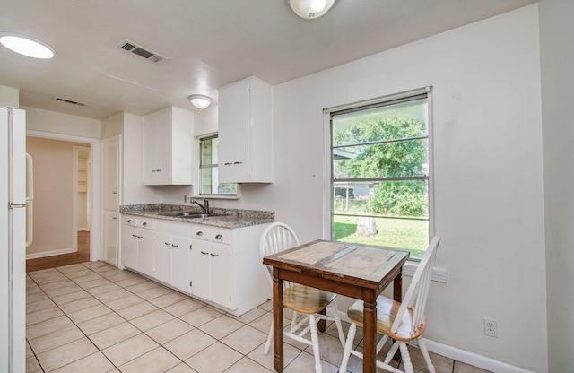 1708 S Park Dr, Alvin, TX 77511 - kitchen with freestanding refrigerator, light tile patterned floors, and white cabinetry