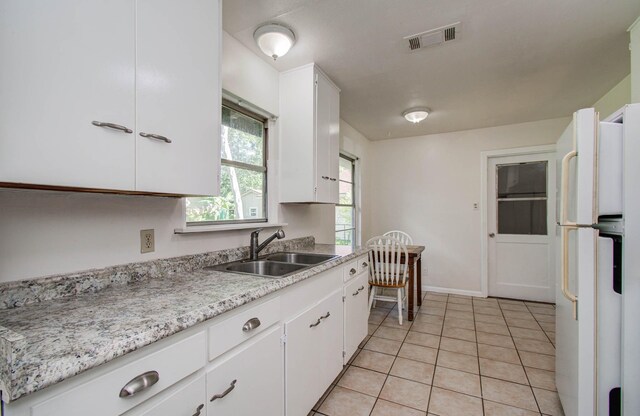 1708 S Park Dr, Alvin, TX 77511 - kitchen with freestanding refrigerator, light countertops, white cabinets, and light tile patterned floors