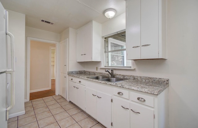 1708 S Park Dr, Alvin, TX 77511 - kitchen featuring light countertops, white cabinetry, light tile patterned floors, and freestanding refrigerator