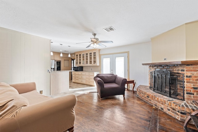 3310 Lake Heights Dr, Waco, TX 76708 - living area with light wood-type flooring, a brick fireplace, ceiling fan, french doors, and a textured ceiling