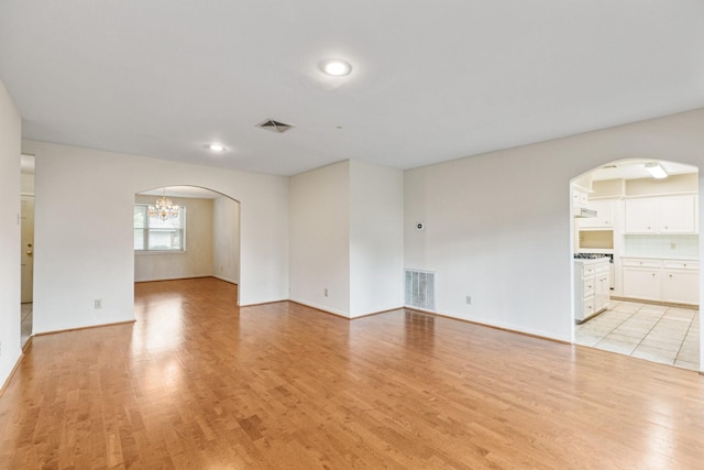 9622 Highmeadow Dr, Houston, TX 77063 - unfurnished living room with arched walkways, light wood-style floors, and a chandelier