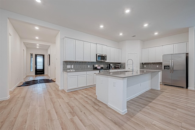 23722 Canolo Grove Ln, New Caney, TX 77357 - kitchen featuring stainless steel appliances, light wood-style floors, tasteful backsplash, white cabinets, and recessed lighting