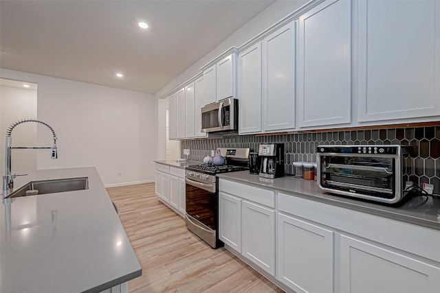 23722 Canolo Grove Ln, New Caney, TX 77357 - kitchen featuring stainless steel appliances, light wood-style floors, tasteful backsplash, recessed lighting, and white cabinets