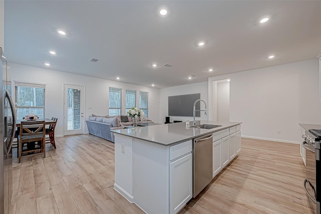 23722 Canolo Grove Ln, New Caney, TX 77357 - kitchen with stainless steel appliances, light wood finished floors, recessed lighting, white cabinetry, and a kitchen island with sink