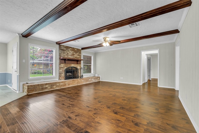 8115 Winding Oak Ln, Spring, TX 77379 - unfurnished living room with beamed ceiling, wood finished floors, a textured ceiling, a brick fireplace, and a ceiling fan