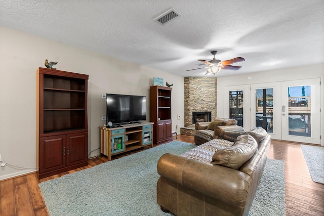 145 Capetown, Montgomery, TX 77356 - living area with wood finished floors, a textured ceiling, a fireplace, and a ceiling fan