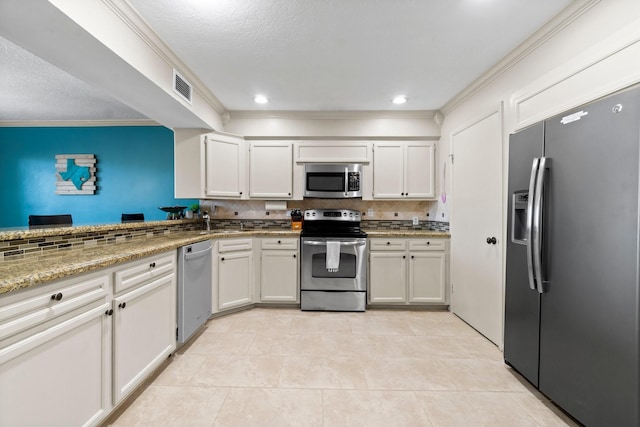 145 Capetown, Montgomery, TX 77356 - kitchen featuring stainless steel appliances, tasteful backsplash, light tile patterned floors, crown molding, and white cabinetry