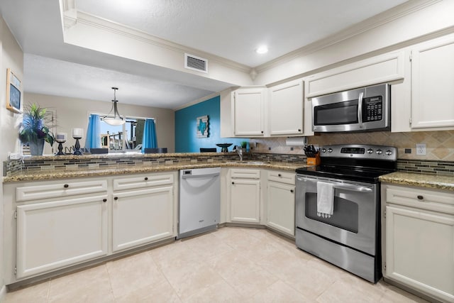 145 Capetown, Montgomery, TX 77356 - kitchen with appliances with stainless steel finishes, crown molding, tasteful backsplash, white cabinets, and pendant lighting
