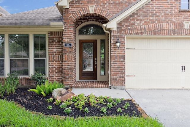 3112 Rock Brook Falls Ln, League City, TX 77573 - view of exterior entry featuring brick siding, a garage, concrete driveway, and a shingled roof
