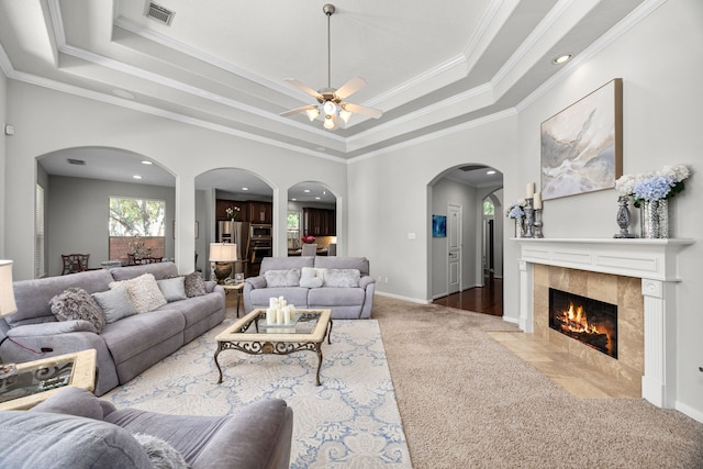 4402 Eden Point Ln, Katy, TX 77494 - living room featuring carpet, a tray ceiling, a ceiling fan, crown molding, and arched walkways
