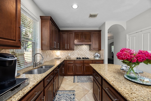 4402 Eden Point Ln, Katy, TX 77494 - kitchen featuring arched walkways, decorative backsplash, cooktop, light stone counters, and light tile patterned floors