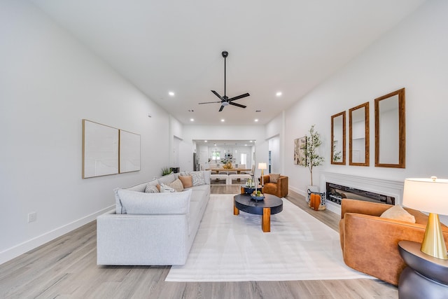 25050 Shady Oak Dr, Hockley, TX 77447 - living room featuring light wood-style flooring, a ceiling fan, a glass covered fireplace, and recessed lighting