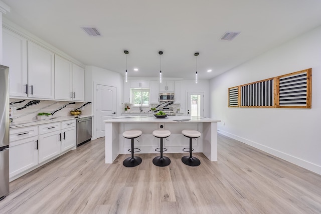 25050 Shady Oak Dr, Hockley, TX 77447 - kitchen featuring stainless steel appliances, backsplash, white cabinets, light wood-type flooring, and light countertops