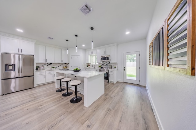 25050 Shady Oak Dr, Hockley, TX 77447 - kitchen with stainless steel appliances, white cabinetry, light countertops, light wood-style flooring, and a breakfast bar area