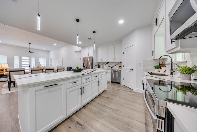25050 Shady Oak Dr, Hockley, TX 77447 - kitchen with stainless steel appliances, ceiling fan, light wood finished floors, white cabinetry, and recessed lighting