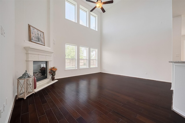 4142 Regal Stone Ln, Sugar Land, TX 77479 - unfurnished living room featuring a ceiling fan, a glass covered fireplace, wood finished floors, and a towering ceiling