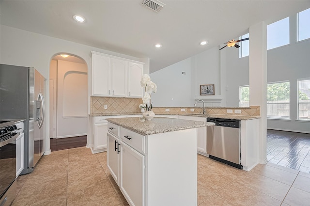 4142 Regal Stone Ln, Sugar Land, TX 77479 - kitchen with appliances with stainless steel finishes, arched walkways, backsplash, ceiling fan, and light tile patterned floors