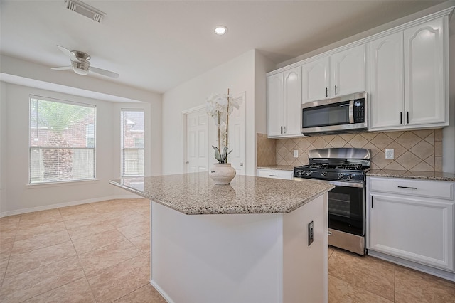 4142 Regal Stone Ln, Sugar Land, TX 77479 - kitchen with stainless steel appliances, light stone counters, backsplash, white cabinetry, and light tile patterned floors