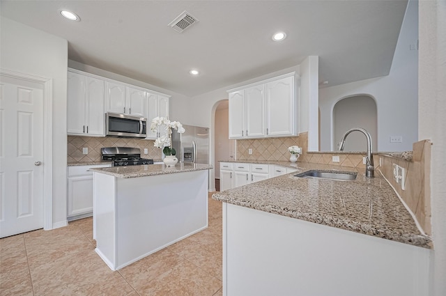 4142 Regal Stone Ln, Sugar Land, TX 77479 - kitchen featuring arched walkways, stainless steel appliances, light stone counters, white cabinetry, and recessed lighting