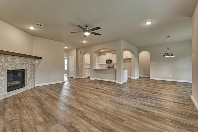 10477 Valley Dr N, Willis, TX 77318 - unfurnished living room featuring ceiling fan, wood finished floors, a brick fireplace, recessed lighting, and arched walkways