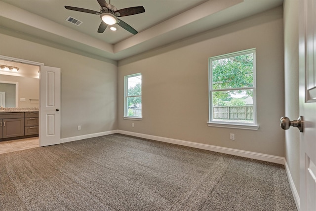 10477 Valley Dr N, Willis, TX 77318 - unfurnished bedroom featuring light carpet, ensuite bathroom, a tray ceiling, and ceiling fan