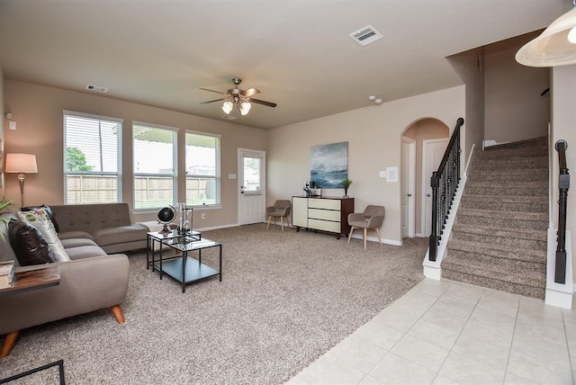 3514 Marquesa Ln, Houston, TX 77084 - living area featuring light colored carpet, stairway, ceiling fan, arched walkways, and light tile patterned flooring