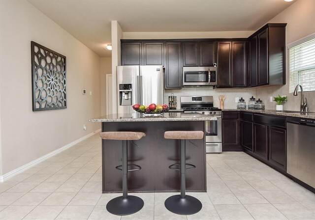 3514 Marquesa Ln, Houston, TX 77084 - kitchen featuring appliances with stainless steel finishes, light stone countertops, a kitchen breakfast bar, a kitchen island, and light tile patterned flooring